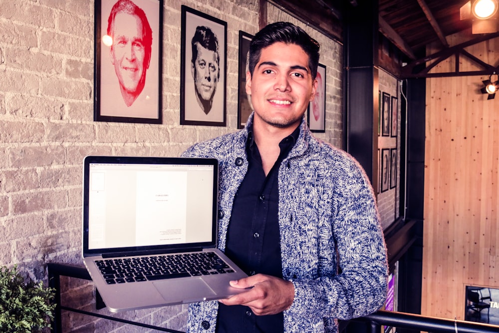 man holding MacBook Pro