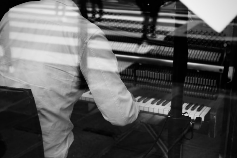 man playing electronic keyboard inside glass house