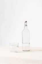 rocks glass beside half empty bottle on white surface