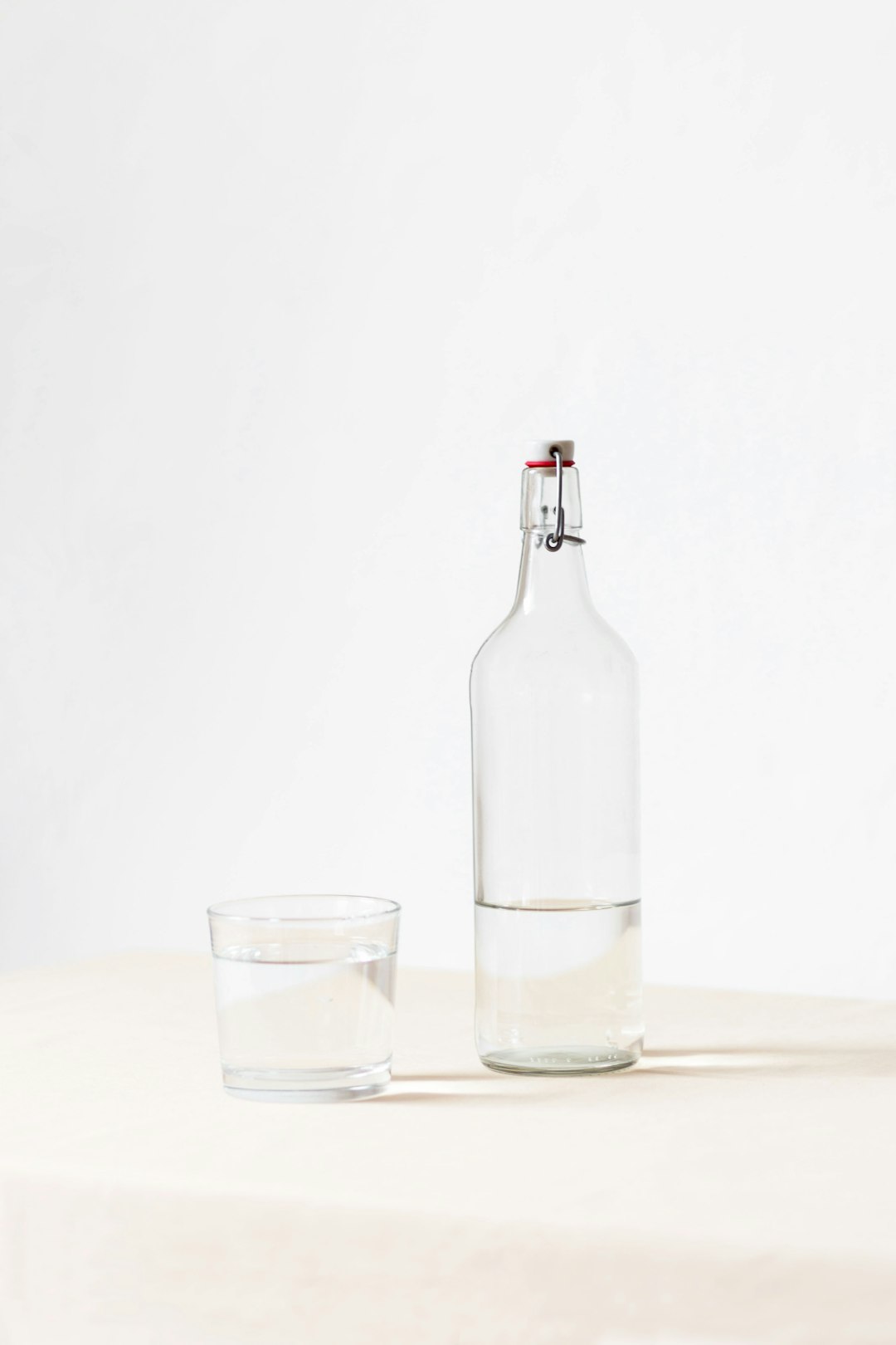  rocks glass beside half empty bottle on white surface bottle