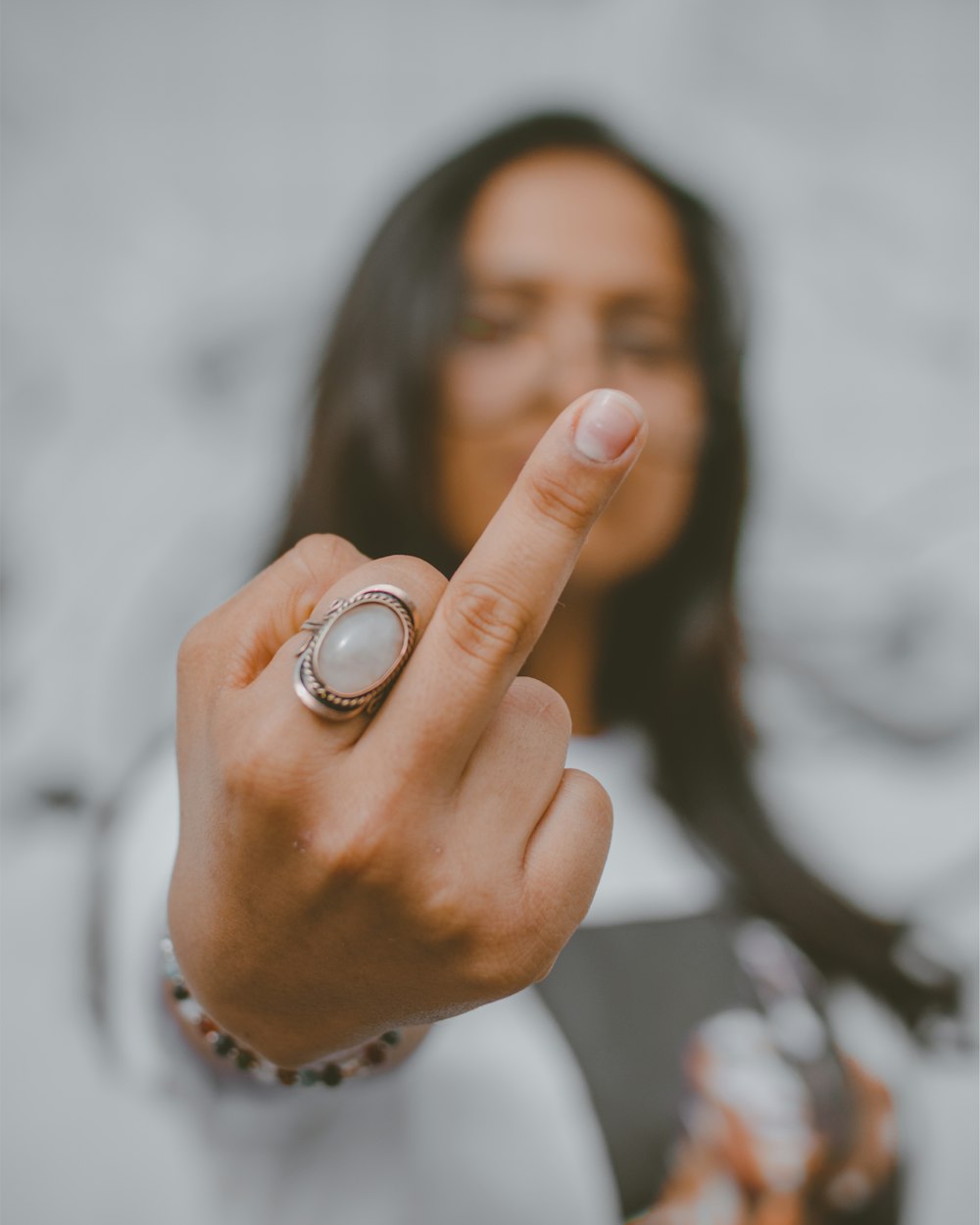 person's middle finger and silver-colored ring