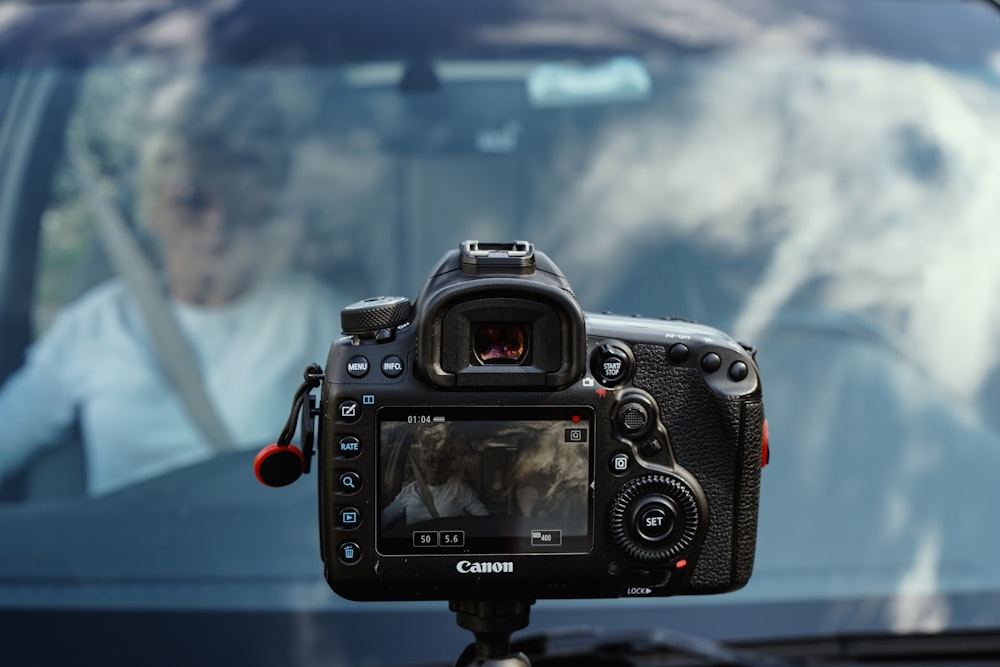 black Canon camera taking photo of man inside vehicle