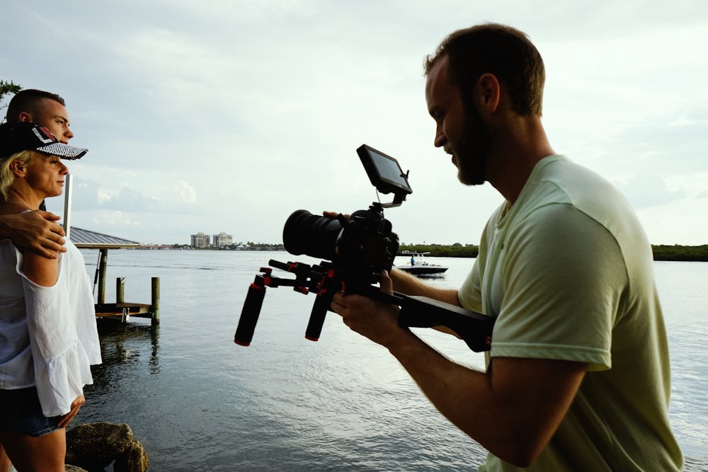 man taking photo of man and woman standing on dock