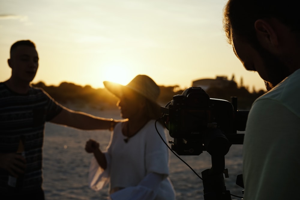 person taking photo of man and woman during golden hour