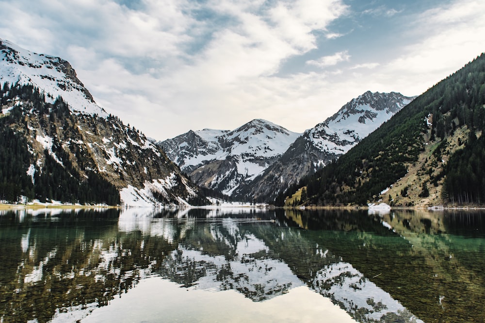 snow covered mountains near body of water