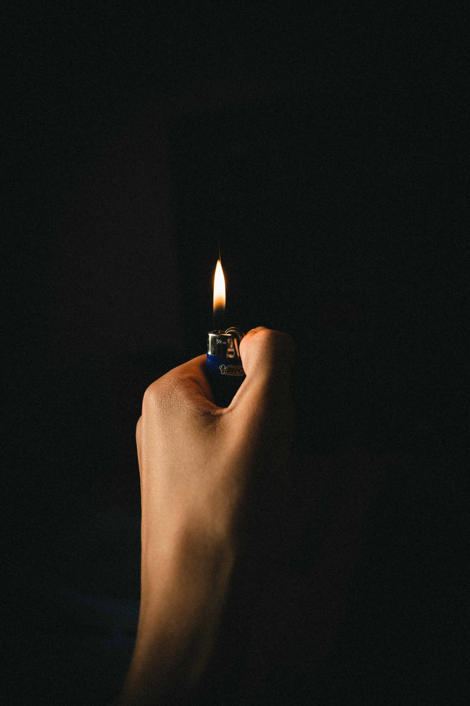 A compact lighter held against a dark background