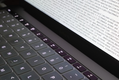 Close-up of hands typing code on a glowing laptop keyboard.