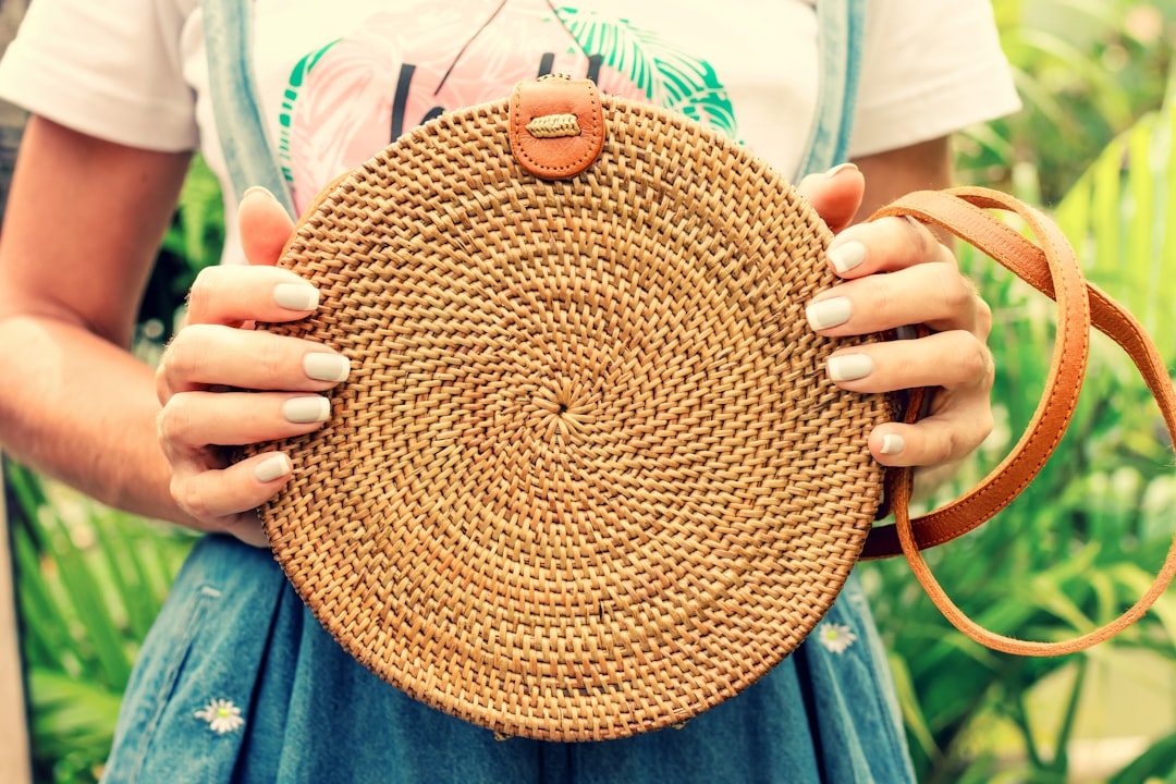 woman holding brown wicker crossbody bag