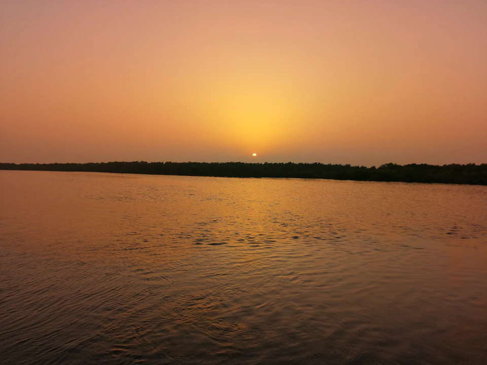 Serene sunset over calm waters reflects vibrant sunset colors in the evening sky