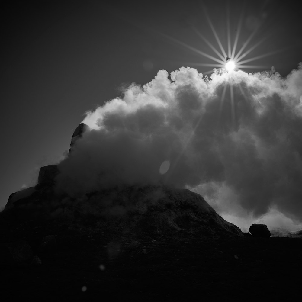 a black and white photo of a mountain with clouds