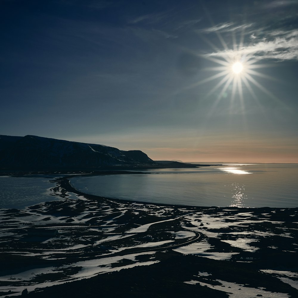 the sun is shining over the water and sand