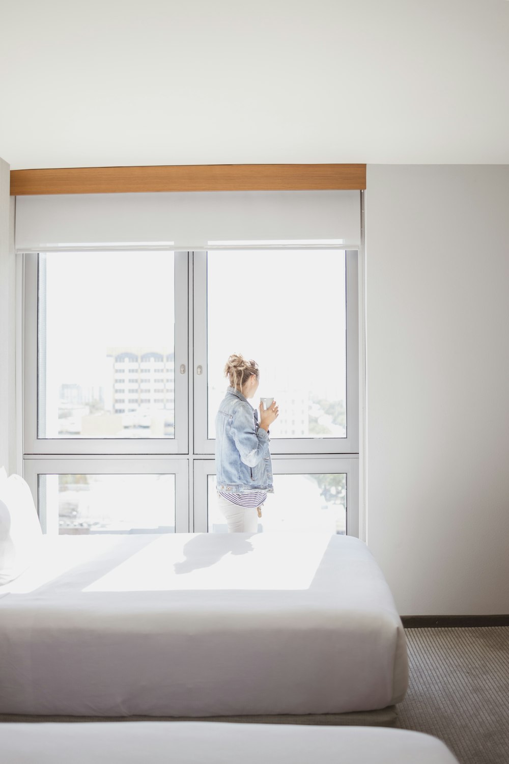 Frau beobachtet Glasfenster in der Nähe eines leeren Bettes
