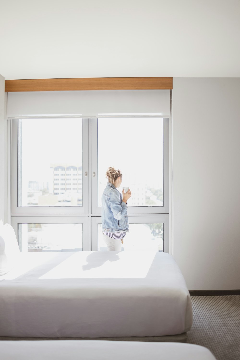 woman watching on glass window near empty bed