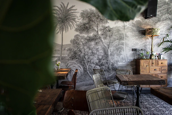 The cozy interior of Tropicalia Açaí with tropical plants, wooden furniture, and colorful mural walls.