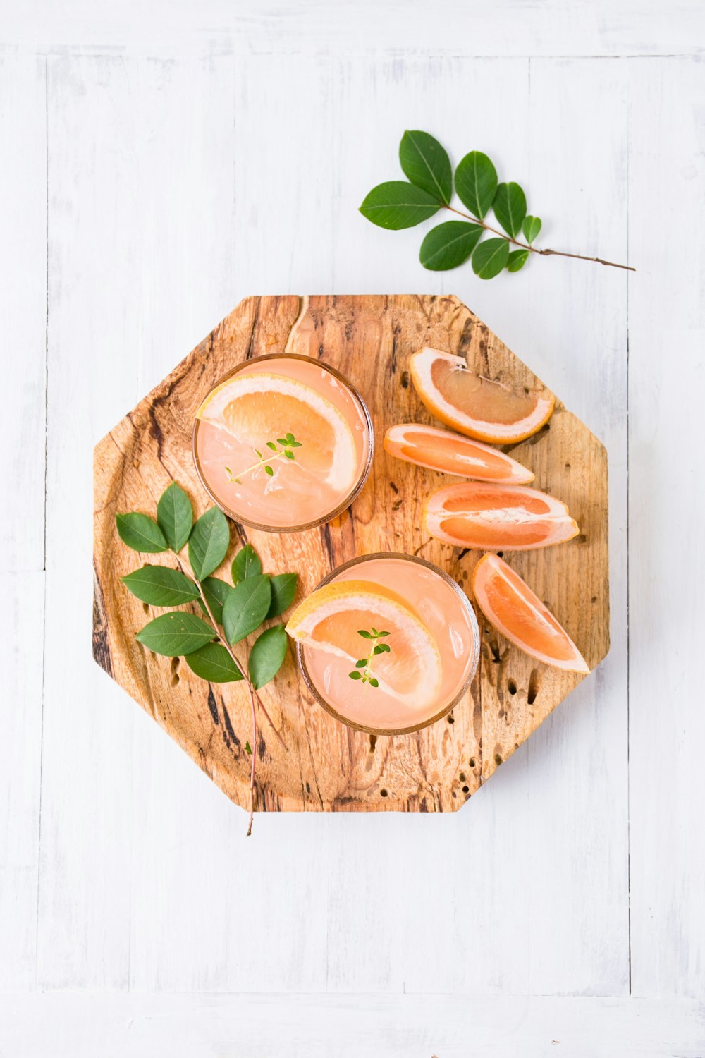 a wooden plate topped with sliced oranges on top of a white table