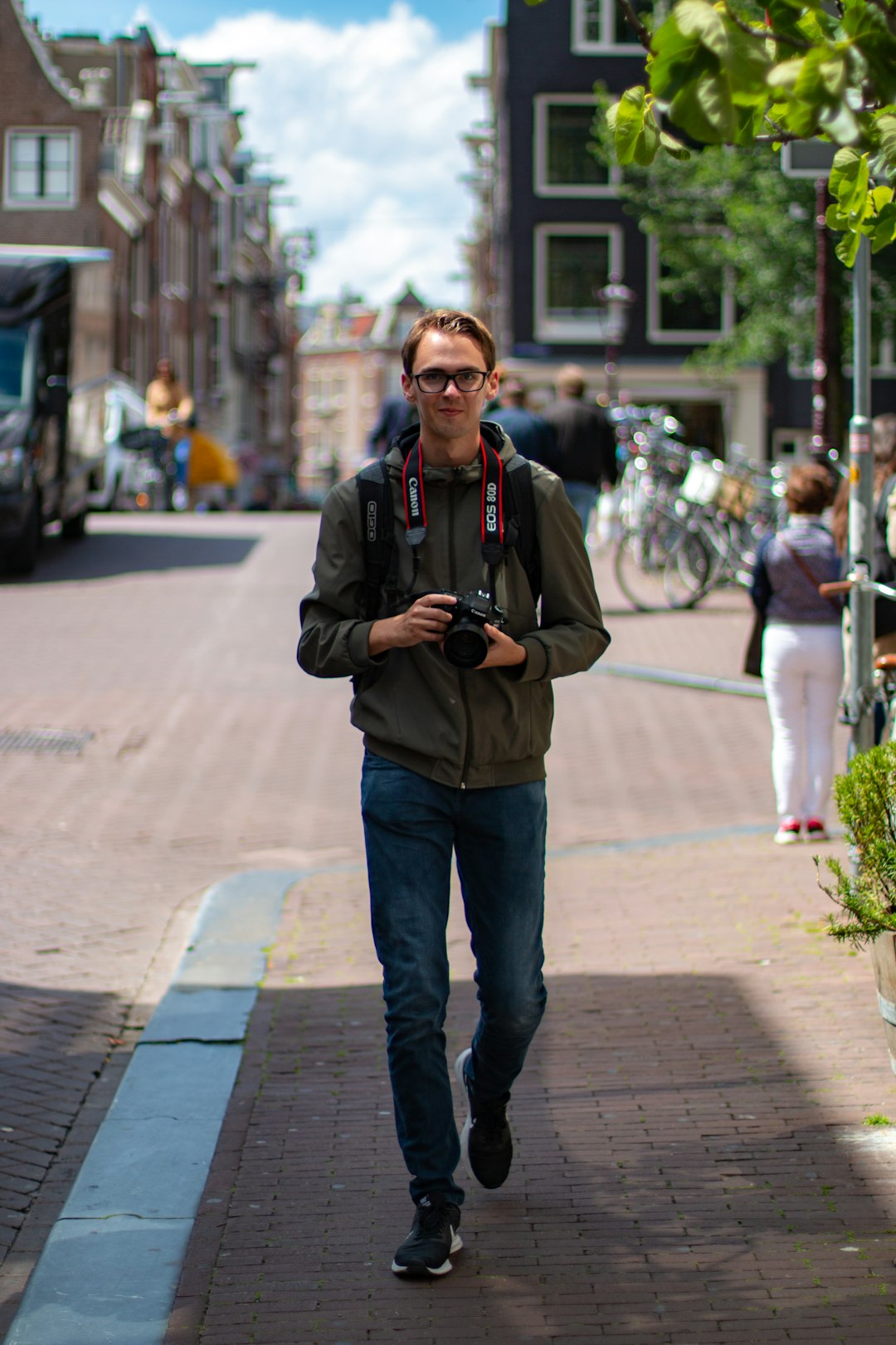 man holding black DSLR camera standing on sidewalk during daytime