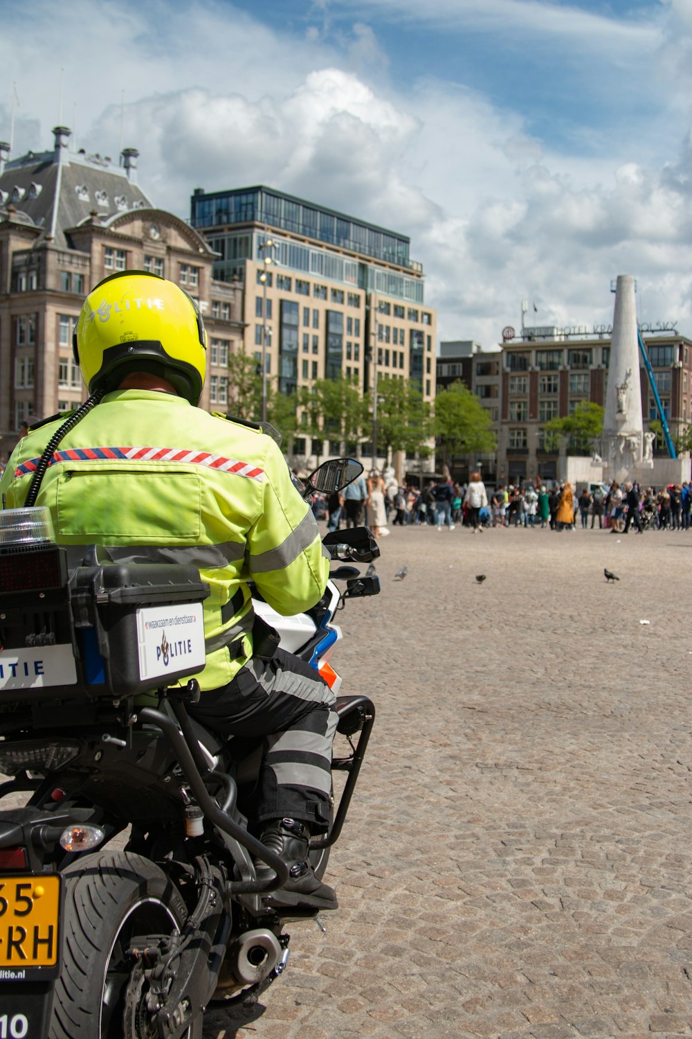 man in green jacket riding motorcycle in front of building during daytime