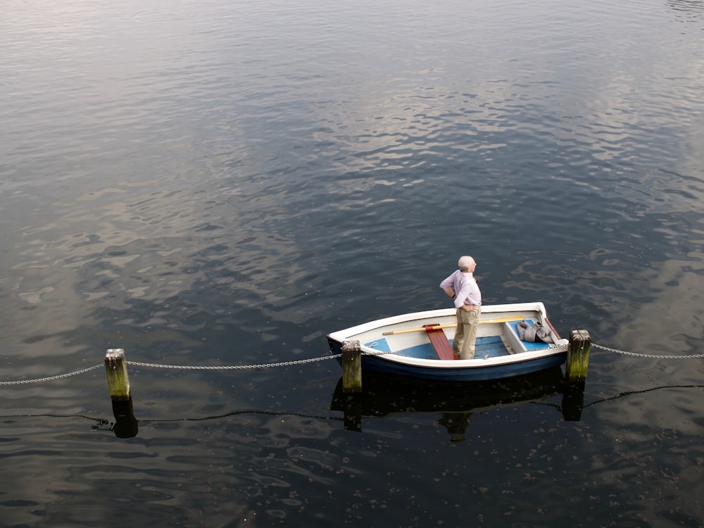 man in white long-sleeved shirt standing on white jon boat during daytime