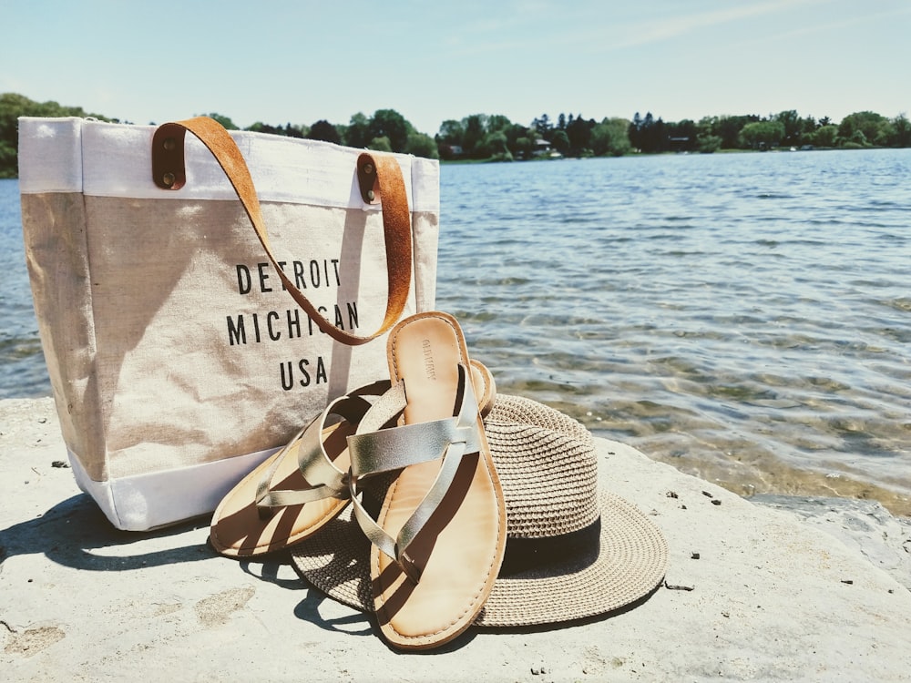 hat, sandals, and bag near water