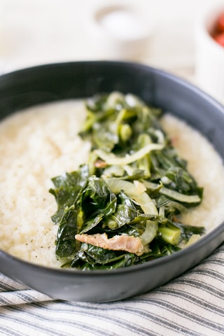a bowl filled with rice and greens on top of a table
