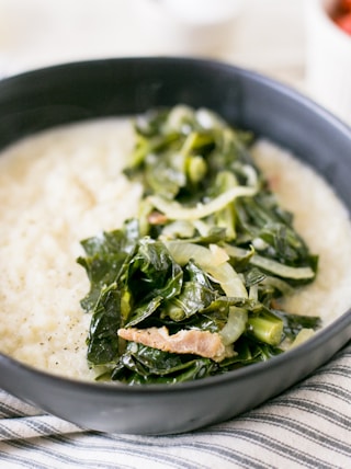 a bowl filled with rice and greens on top of a table