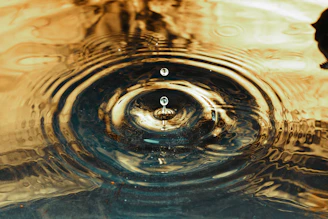 Close-up of a golden ripple expanding from a pill button on a dark background.