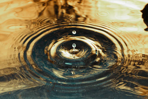 Close-up of a golden ripple expanding from a pill button on a dark background.