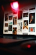 A laptop is displaying a Pinterest-like webpage, showing a grid of various images, including landscapes, close-up shots of hands holding a phone, and artistic photographs. The scene is dimly lit with a prominent red light reflecting off the screen, creating a moody ambiance.