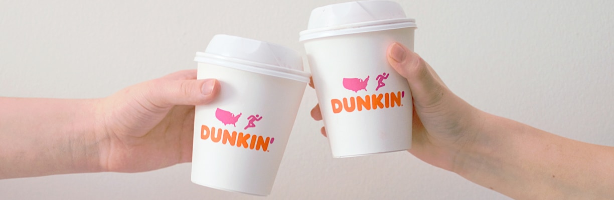 two people with white Dunkin' Donuts paper cups