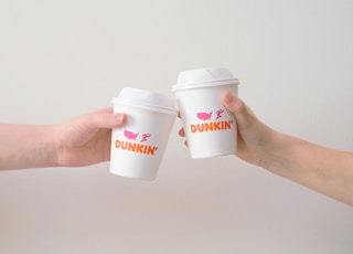 two people with white Dunkin' Donuts paper cups