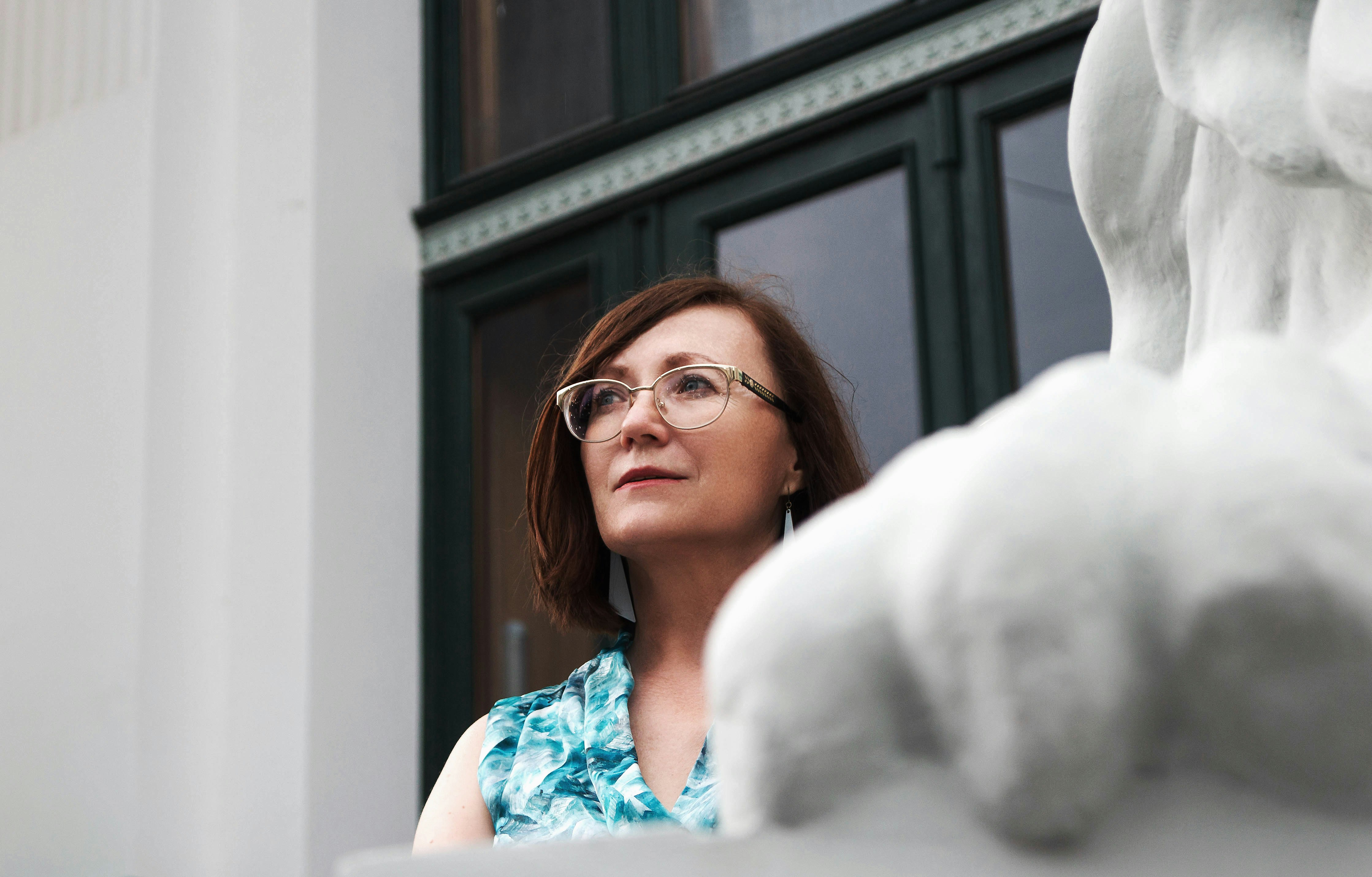 woman in blue and teal to by glass window