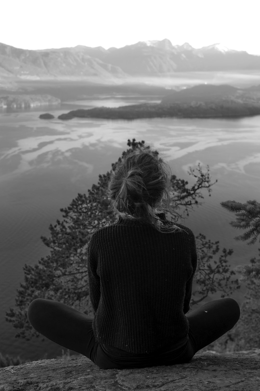 woman wearing black shirt sitting facing on mountain