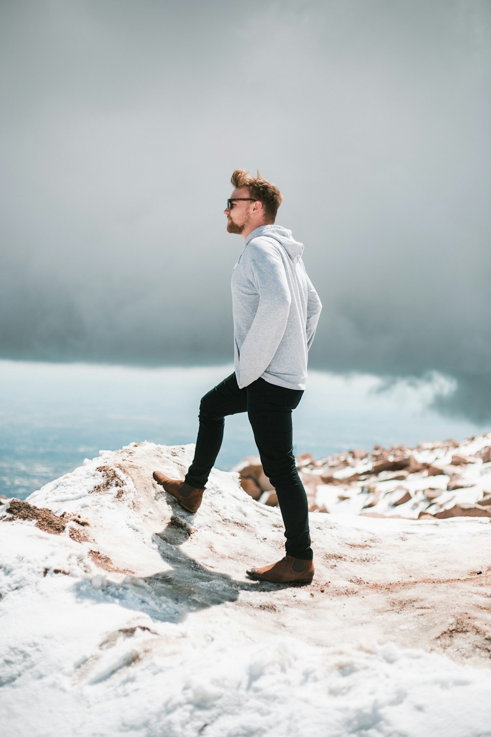 man standing at the cliff under dark clouds