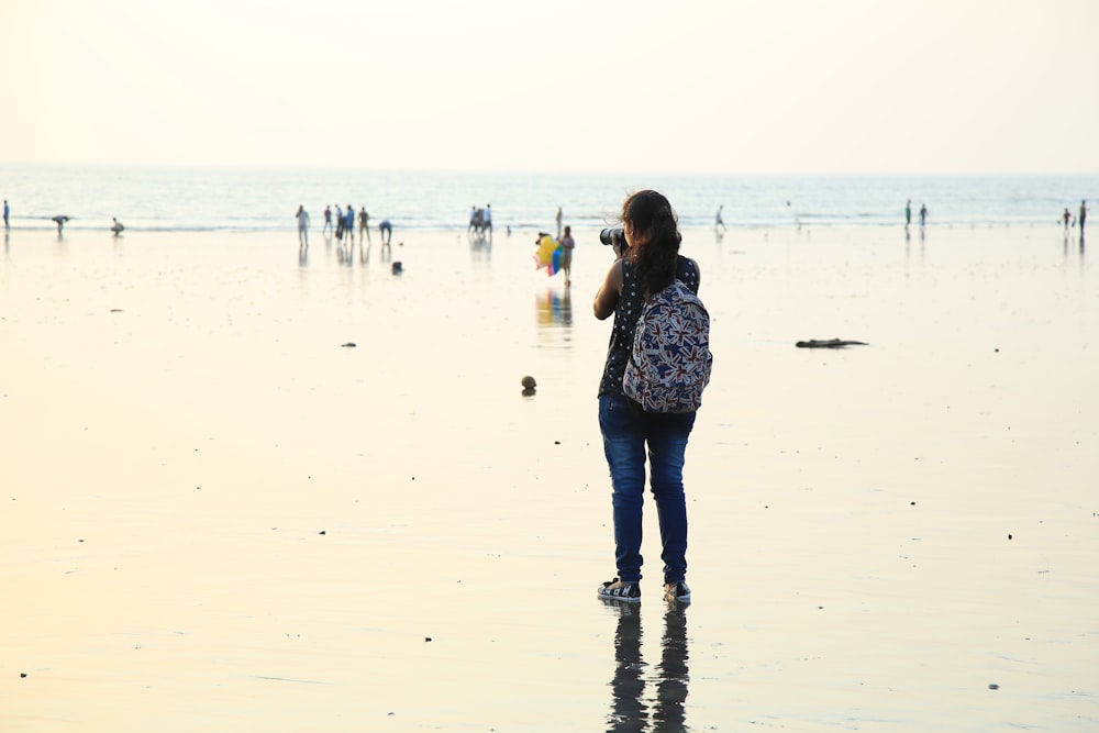 woman standing holding camera wearing backpack