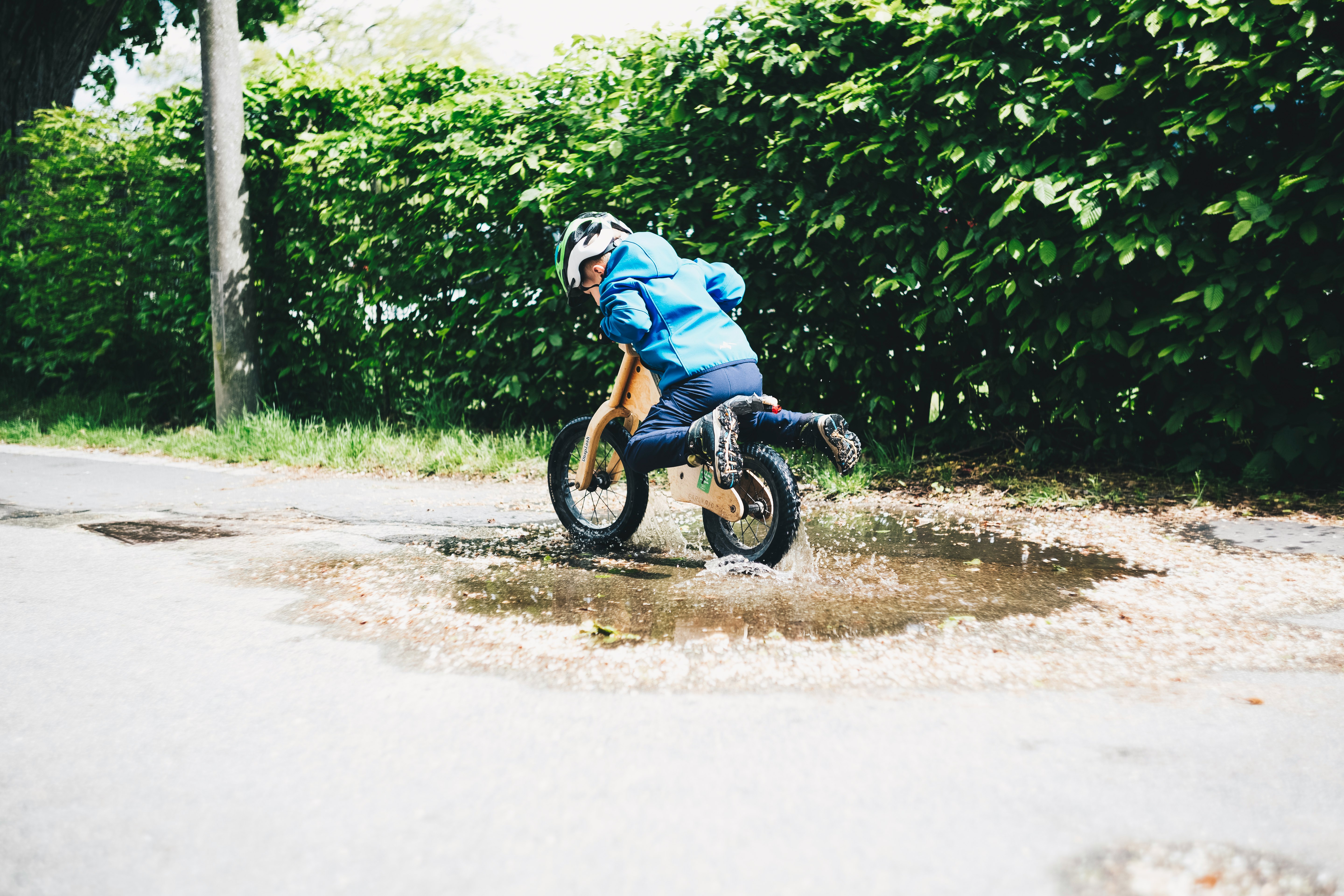 Young boy with training bike balance bike rides through the puddle. Made with Canon 5d Mark III and loved analog lens, Helios 44M 2.0 / 58mm (Year: 1977)
