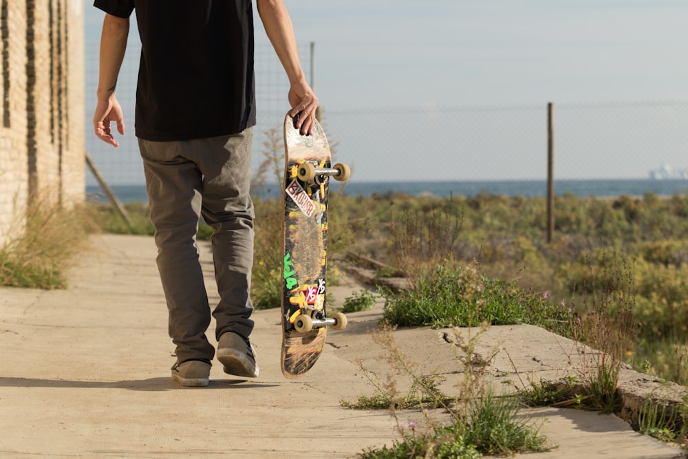 man carrying skateboard on concrete pavement