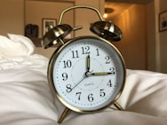 round gray stainless steel and white alarm clock displaying 12:15 time