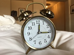 round gray stainless steel and white alarm clock displaying 12:15 time