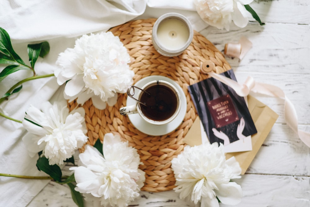 flat lay photography of teacup surrounded by flowers