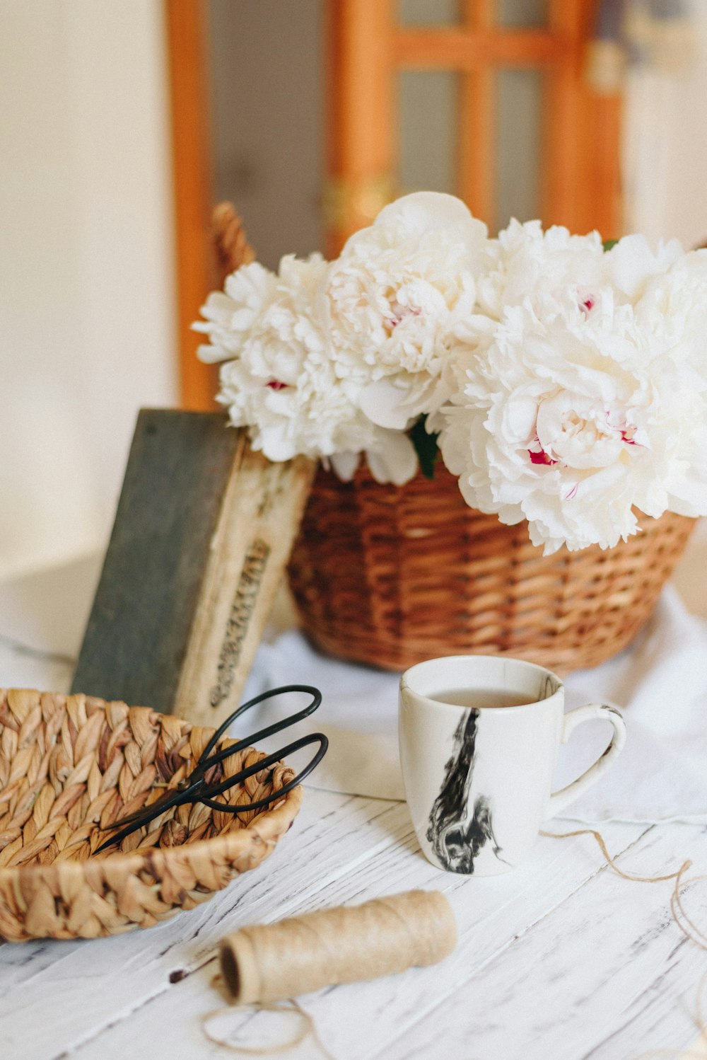 filled white ceramic mug beside basket and flowers