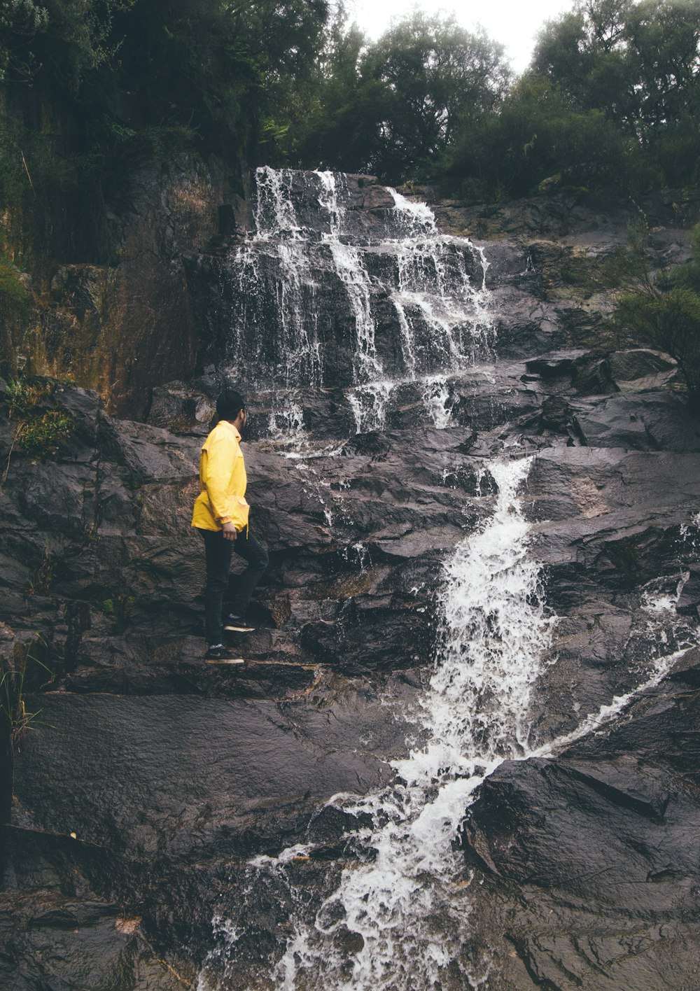 man standing on rock near waterfalls