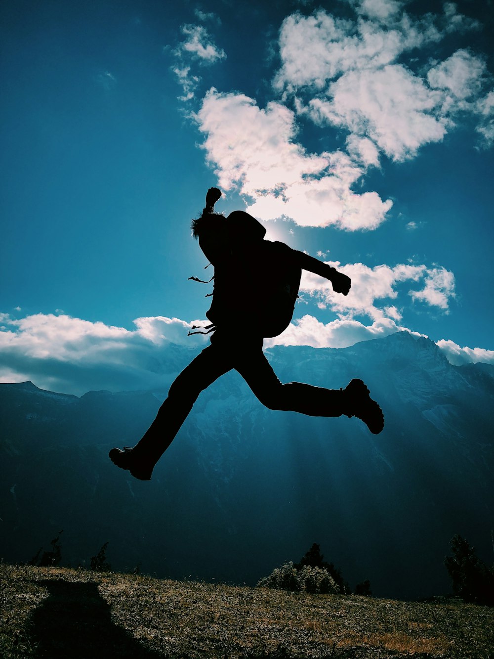 silhouette of person jumping on mountain