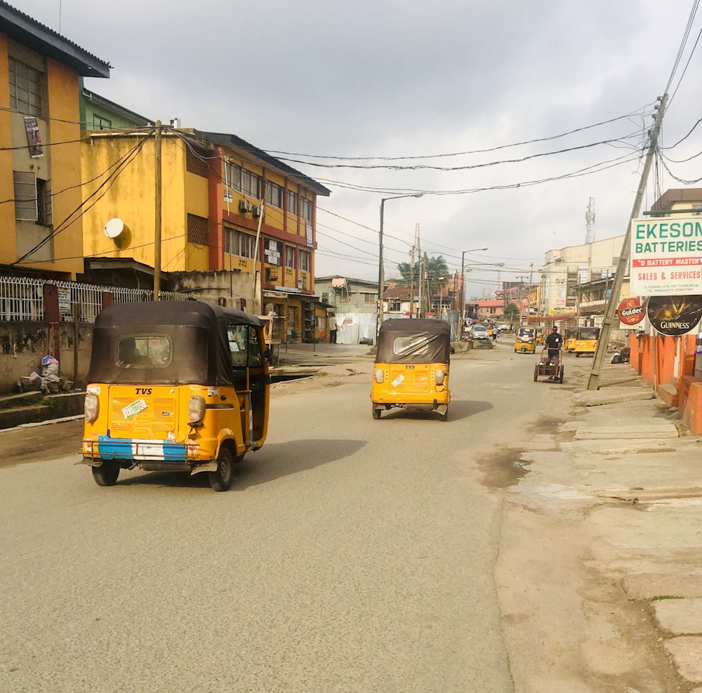 two auto-rickshaw in road between buildings during daytime