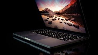 A powerful laptop open on a desk with a scenic view in the background.