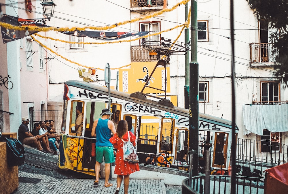 man and woman walking towards cable train near buildings