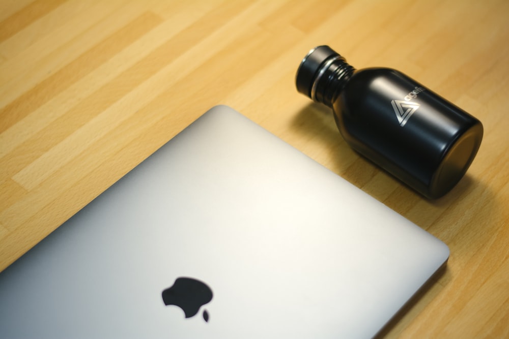 MacBook Pro beside black bottle