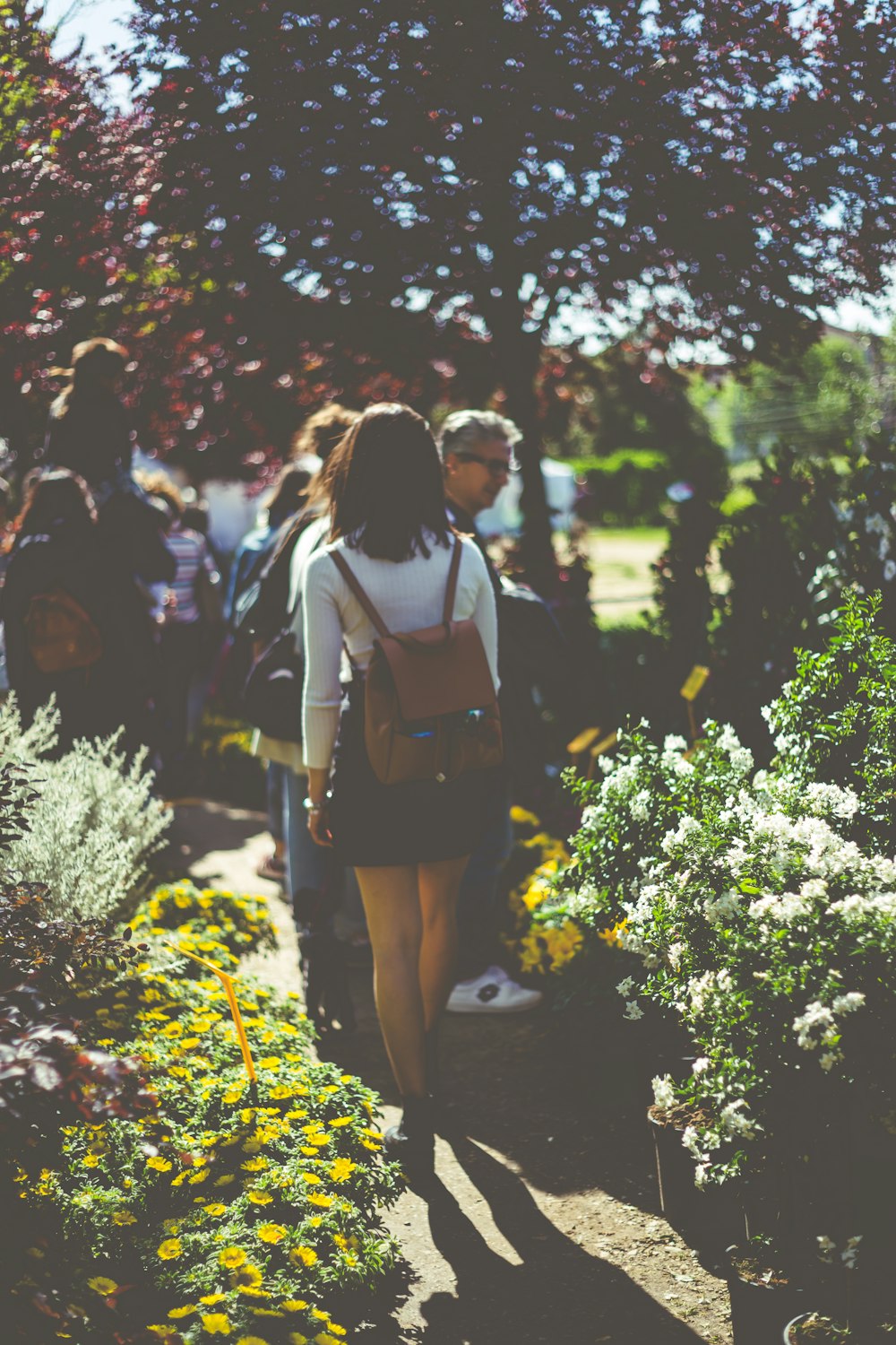 man wearing black skirt walking beside plants