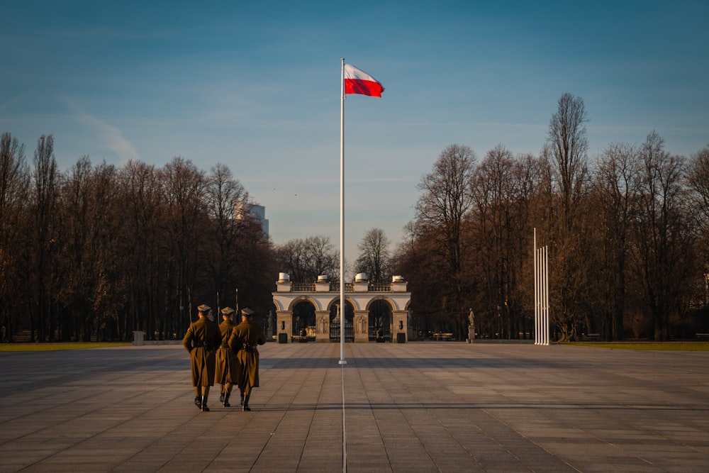 three military soldiers walking at the park near flag pole