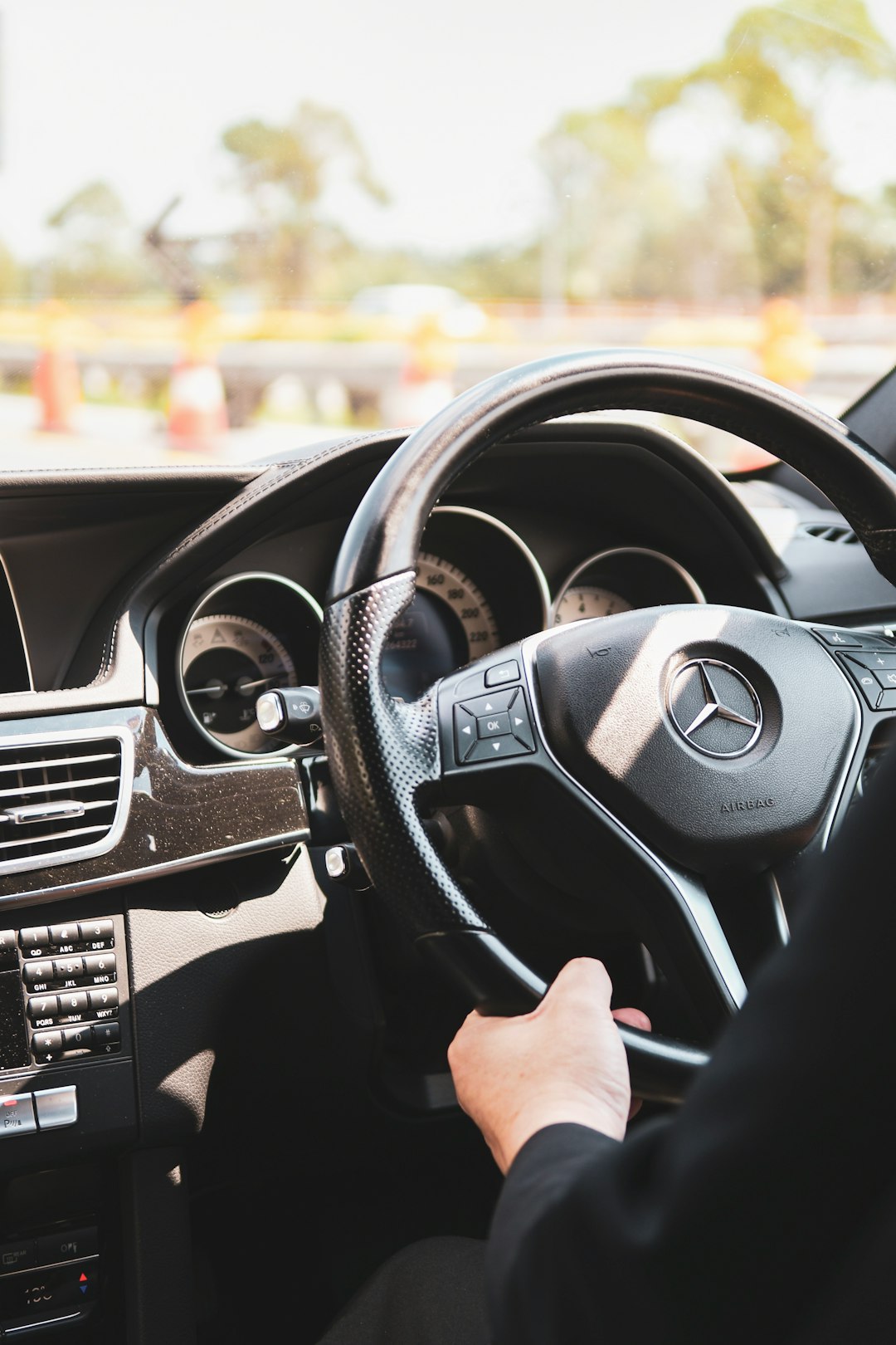 person in black shirt driving holding the mercedesbenz steering wheel