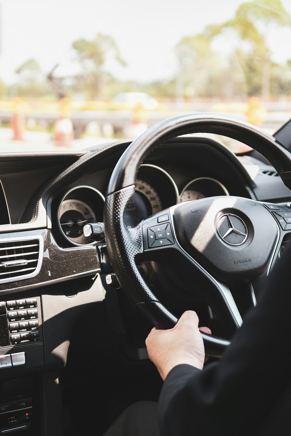 person in black shirt driving holding the mercedesbenz steering wheel